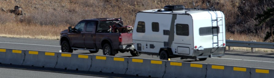 truck towing camper and atv on highway